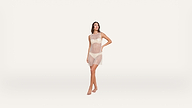 A woman stands barefoot wearing a sheer sleeveless dress over matching lingerie, posing with one hand on her hip against a plain white background.