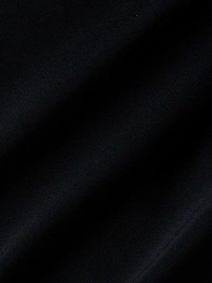 Close-up of black fabric with a smooth texture and subtle diagonal folds, evocative of the elegant drape of the Camilla Monokini with front cutouts, creating soft shadows and highlights across its surface.