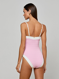 A woman with long brown hair models the Tory Bandeau One-Piece Swimsuit in pink bouclé fabric with white trim, shown from the back against a plain light background.