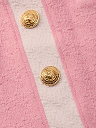 Close-up of the Coco Mini Skirt Cover-Up in pink bouclé fabric with two gold embossed buttons and a vertical off-white stripe—ideal as a chic swimsuit cover-up.