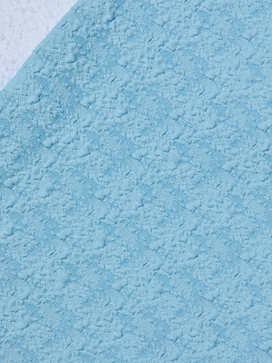 Close-up of the Vanessa High-Waisted Bikini Bottom in light blue, featuring a textured, bouclé-like fabric placed over white—both displaying a soft, fluffy swimwear surface.