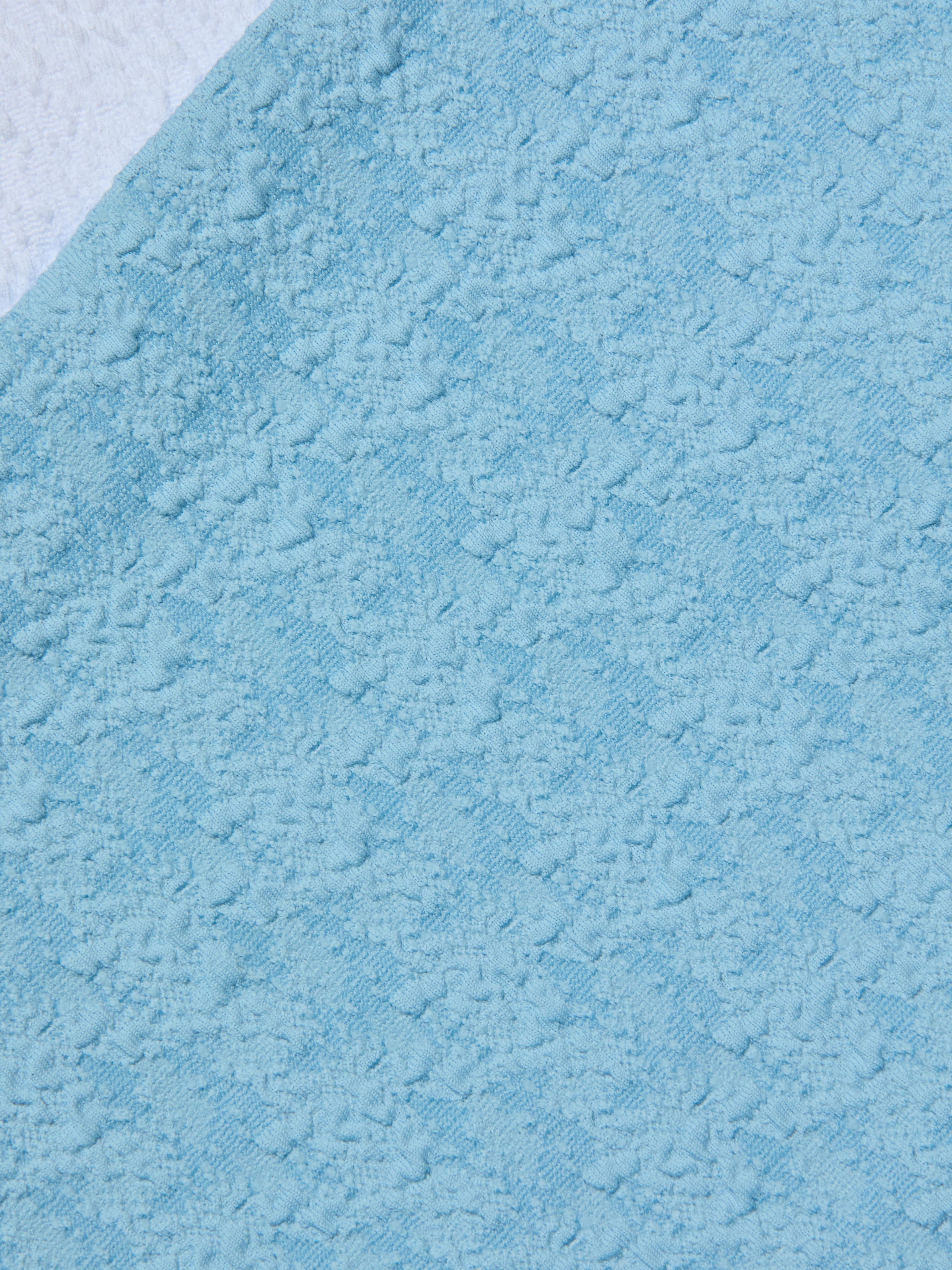 Close-up of the Vanessa High-Waisted Bikini Bottom in light blue bouclé swim fabric, featuring a raised, patterned surface with diagonal lines and soft, fluffy patches throughout.