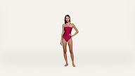 A woman stands confidently in a red one-piece swimsuit against a plain white background, with one hand on her hip and the other relaxed by her side.