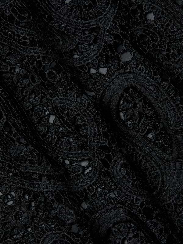 Close-up of the Ansley Cover-Up Dress, featuring intricate black lace fabric with swirling paisley and floral patterns, showcasing textured embroidery and delicate openwork details reminiscent of boho style.