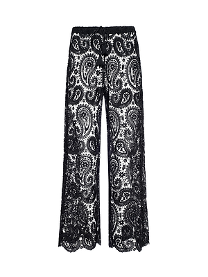 The Geraldine Cover-Up Pant features black paisley crochet with a wide-leg silhouette, intricate pattern, and scalloped hems. These semi-sheer boho pants are ideal for resort wear or relaxed summer style.