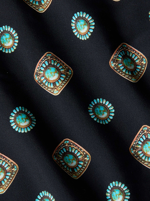 A close-up of the Alexandria Bikini Top’s black fabric, adorned with teal and gold geometric medallion print in alternating round and square motifs, each bordered decoratively with intricate teal details for a textured look.
