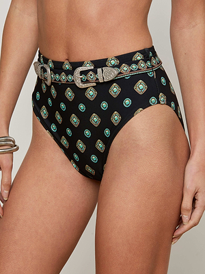 Someone wears the Vanessa High-Waisted Bikini Bottom in black with a turquoise and gold geometric medallion print and an embellished waist belt with a decorative silver buckle, paired with silver bangles on the left wrist against a light gray background.