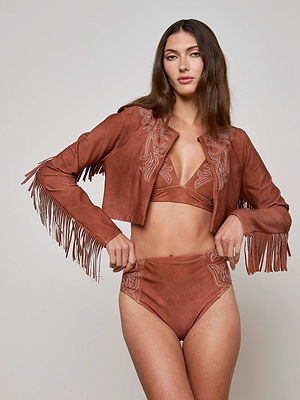 A woman poses against a plain background wearing the L'AGENCE Sale Adeline Cardigan Cover-Up, a suede-look brown fringe jacket paired with a matching bralette and high-waisted embroidered bottoms.