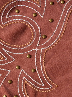Close-up of the Vanessa High-Waisted Bikini Bottom by L'AGENCE Sale, showing brown fabric with white and tan swirling decorative stitching and small gold stud accents.