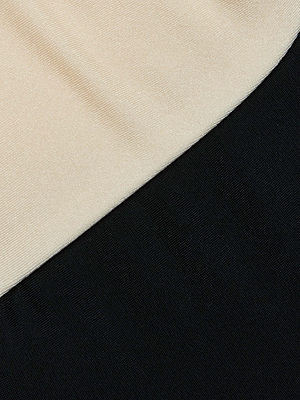 A close-up of the Emilia Bandeau One-Piece Swimsuit by L'AGENCE shows its beige and black color-blocked, subtly textured fabric, highlighting modern swimwear style.