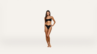 A woman stands on a plain white background wearing a black bikini, facing forward with one hand on her hip and a neutral expression.
