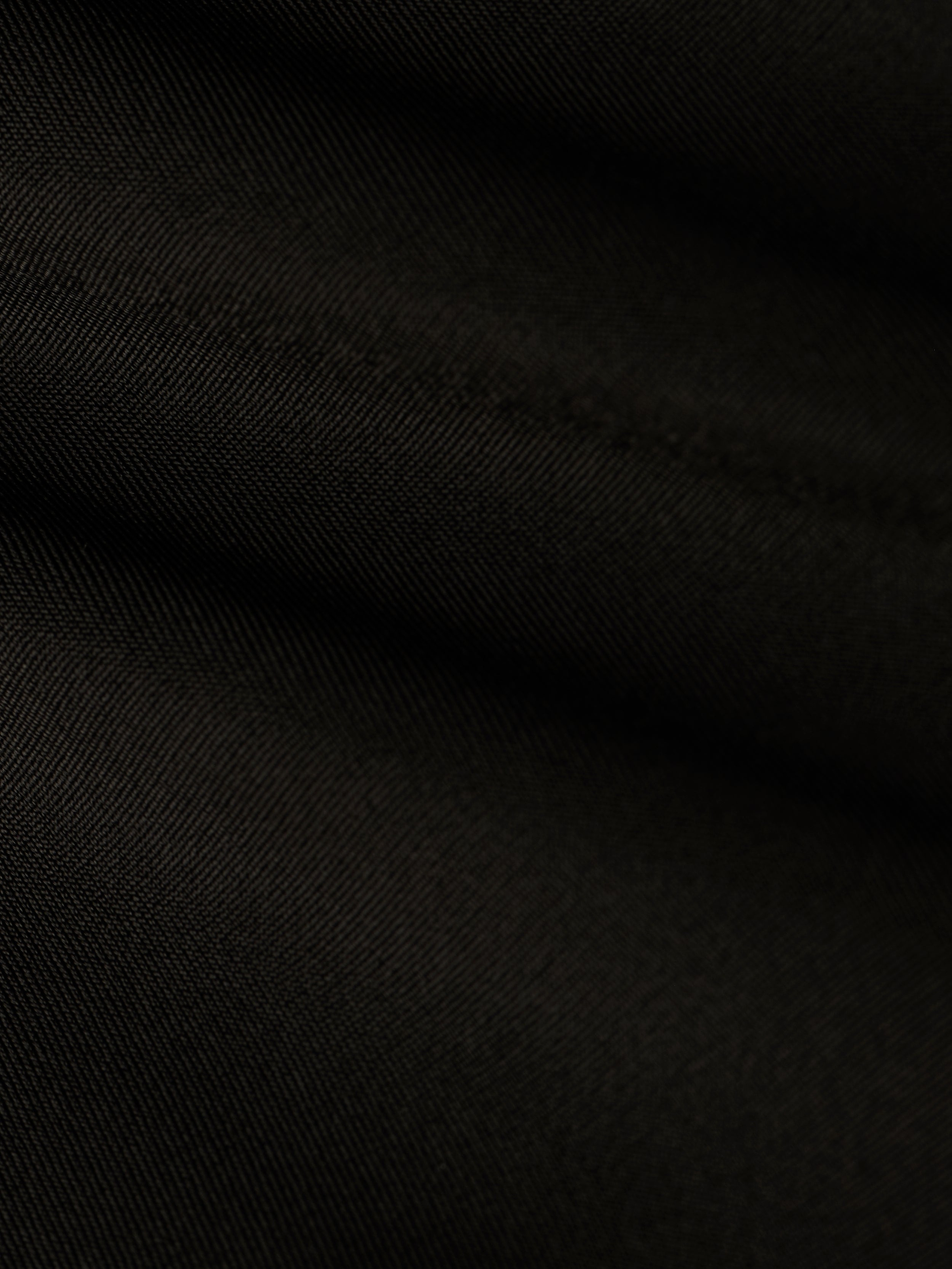 Close-up of black fabric with diagonal weave pattern and soft folds, highlighting the fine texture and subtle highlights on the surface, reminiscent of the refined Ashleigh Bikini Bottom.