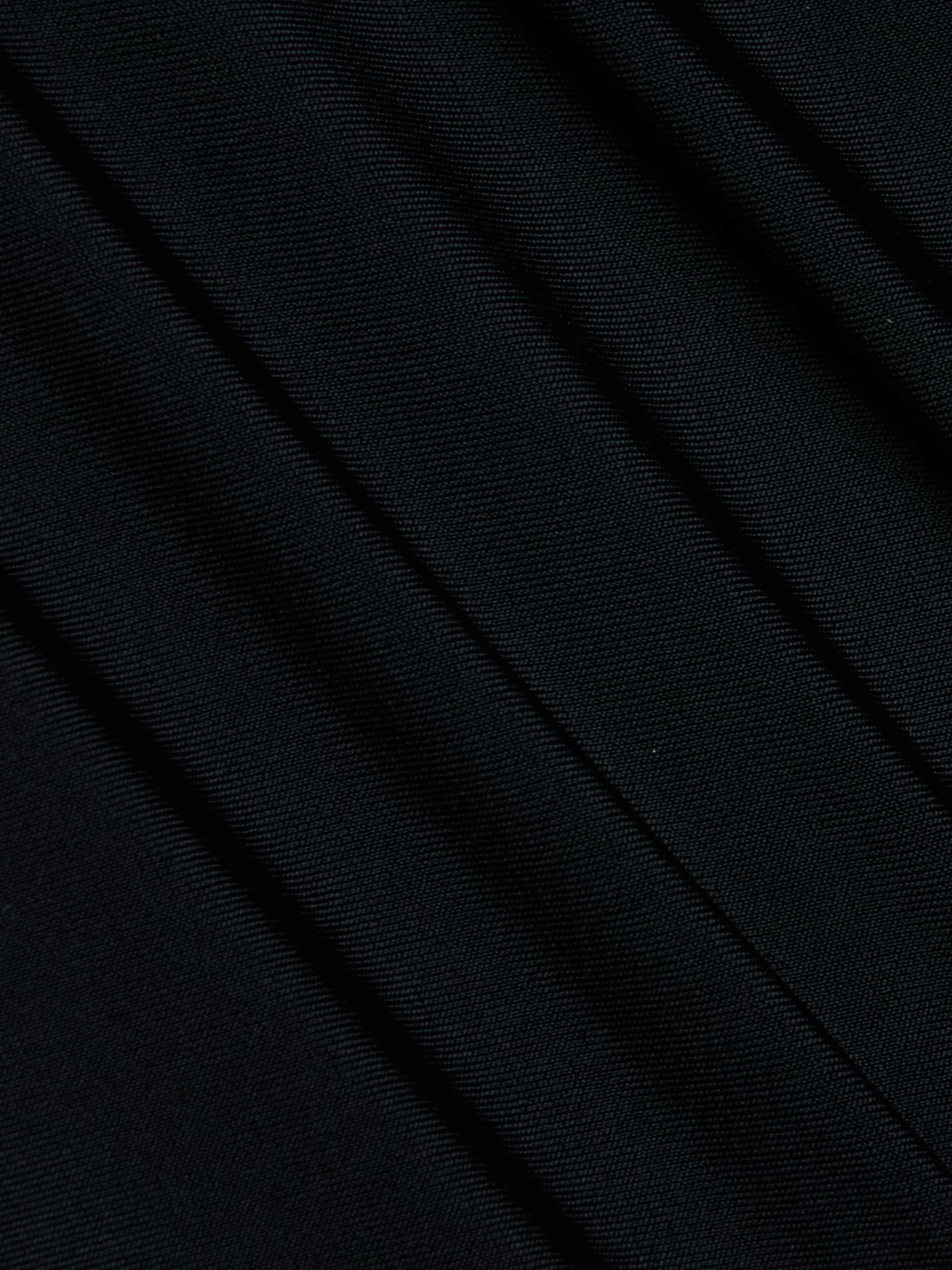 Close-up of the Lambert Paddlesuit’s black four-way stretch nylon fabric, featuring diagonal folds and a fine texture that highlights its detailed weave pattern and the subtle shadows formed by overlapping layers.