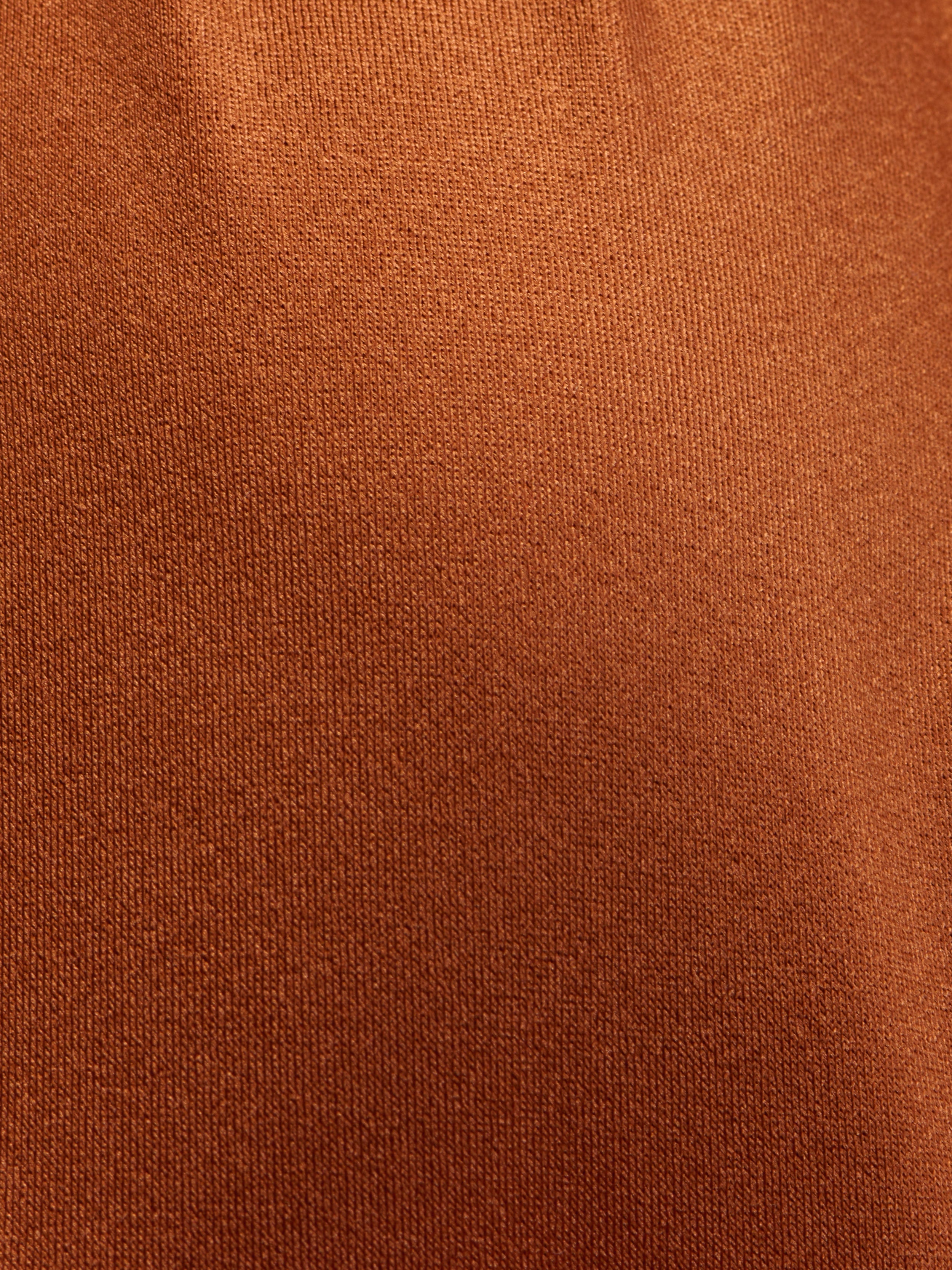 Close-up of the Sirena Halter Bikini Top features a textured, rust-colored fabric with a soft, even weave and gentle folds, highlighted by a subtle bronze shimmer.