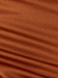 Close-up of rust-colored ribbed fabric displaying horizontal ridges and rich texture, softly lit to highlight the weave and folds—an ideal detail from the Britt Tie-Side Bikini Bottom, designed with adjustable tie sides and moderate coverage.
