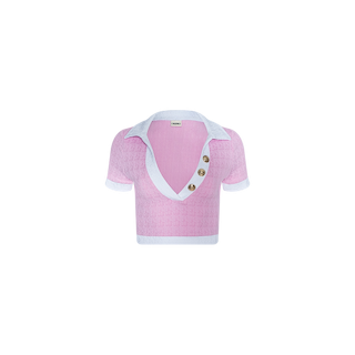 The Anastasia Cropped Rashguard is a short-sleeve, pink knit top made from textured bouclé fabric, showcasing a deep V-neckline, white collar and trim, and three large buttons along one side of the opening. It is displayed against a plain white background.