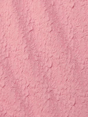 Close-up of the Jean Bikini Bottom’s textured pink bouclé fabric, featuring a soft, uneven surface with raised patterns—perfect for a chic high-leg cut and on-trend poolside style.