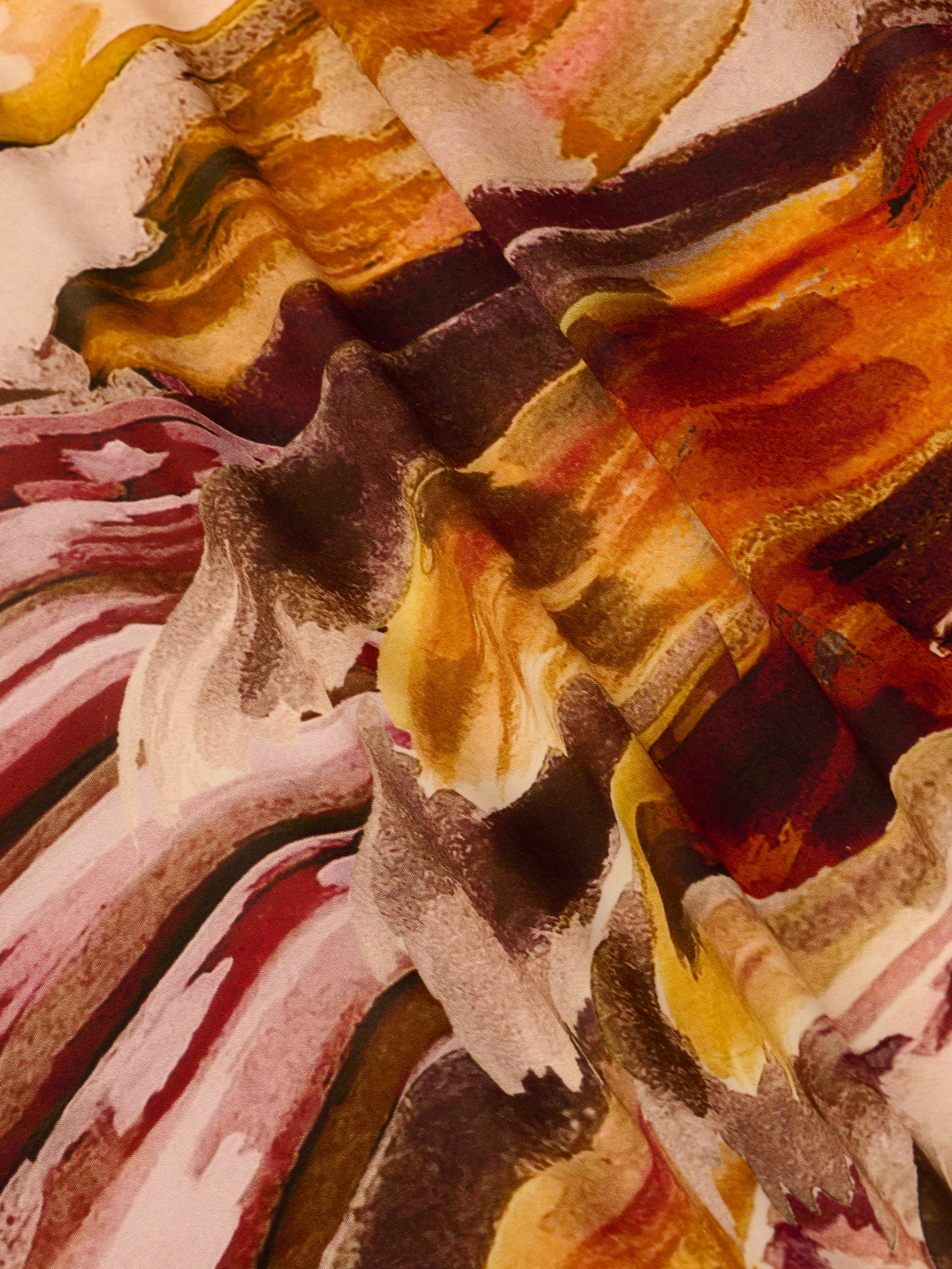 Abstract close-up of the Janus Cover-Up Robe, crafted from viscose chiffon with wavy, brushstroke-like patterns in red, pink, brown, yellow, and cream tones that create a dynamic and textured visual effect.