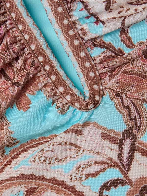 Close-up of the fabric from the Lilou One-Piece Swimsuit, showcasing a brown, pink, and cream floral and polka dot pattern on a light blue background, with gathered seams and decorative stitching.