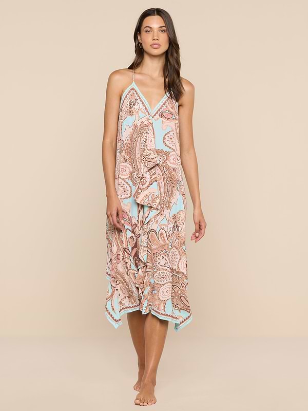 A woman stands barefoot against a white background, wearing the Elise Cover-Up Dress, which features a paisley print, halter neckline, V-neckline, and a flowy midi silhouette.