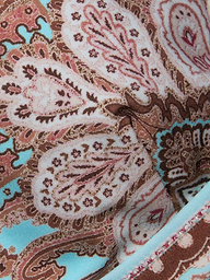 Close-up of the Lexie Bikini Top, featuring colorful fabric with an intricate paisley print in shades of pink, brown, and blue. The detailed stitching and decorative designs are highlighted, along with its adjustable straps.