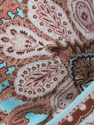 A close-up of the Lexie Bikini Top features a paisley print in brown, pink, and light blue with intricate floral and leaf designs, finished with decorative edge stitching.