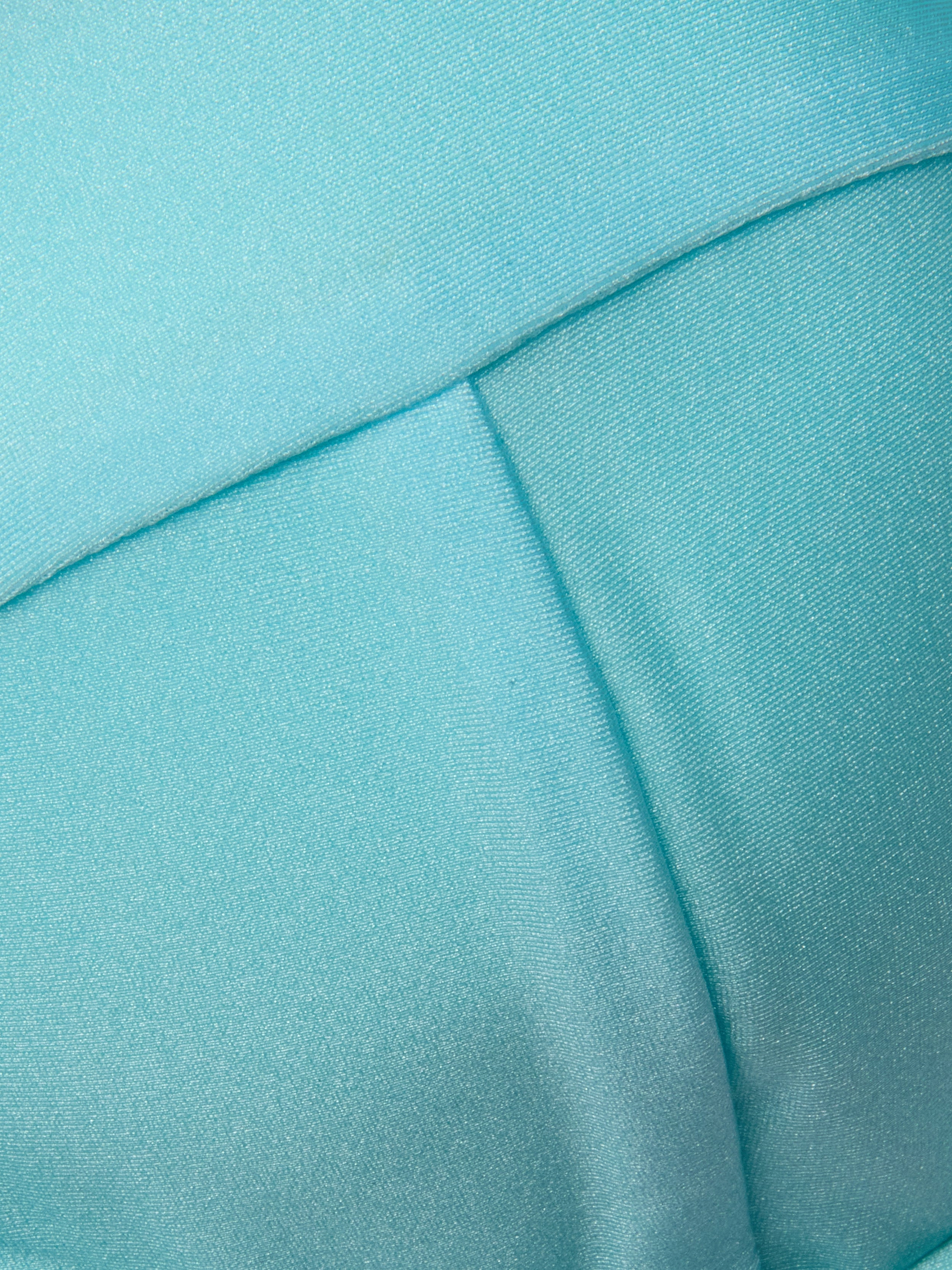 Close-up of light blue fabric with visible stitching and seams, featuring a smooth, slightly shiny texture—ideal for the Alexandria Bikini Top, expertly crafted from UPF 50 swimwear material.