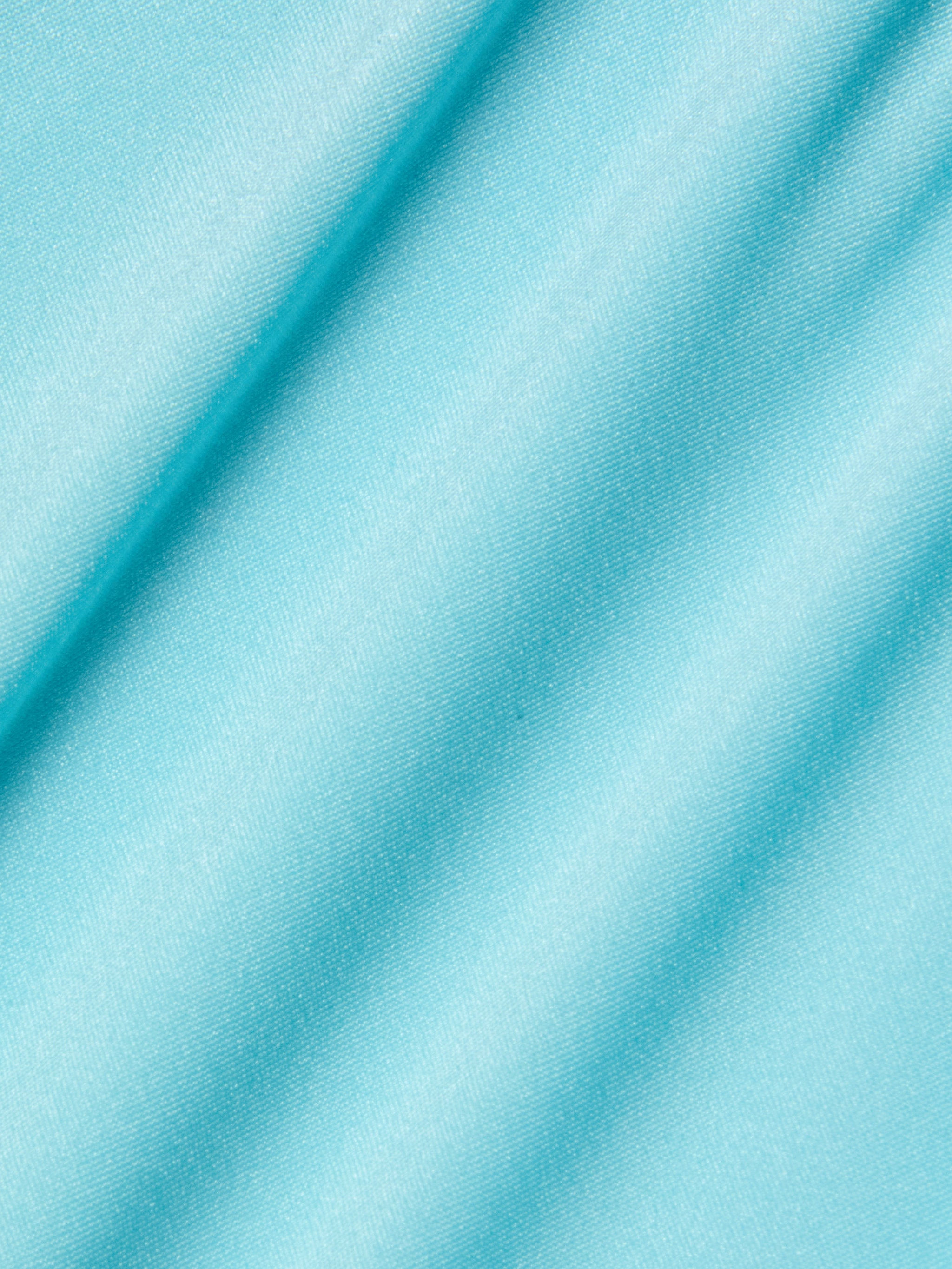 Close-up of the Violet String Bikini Bottom in an ice blue shade, featuring smooth fabric with a soft sheen and diagonal folds that create gentle shadows across the material.