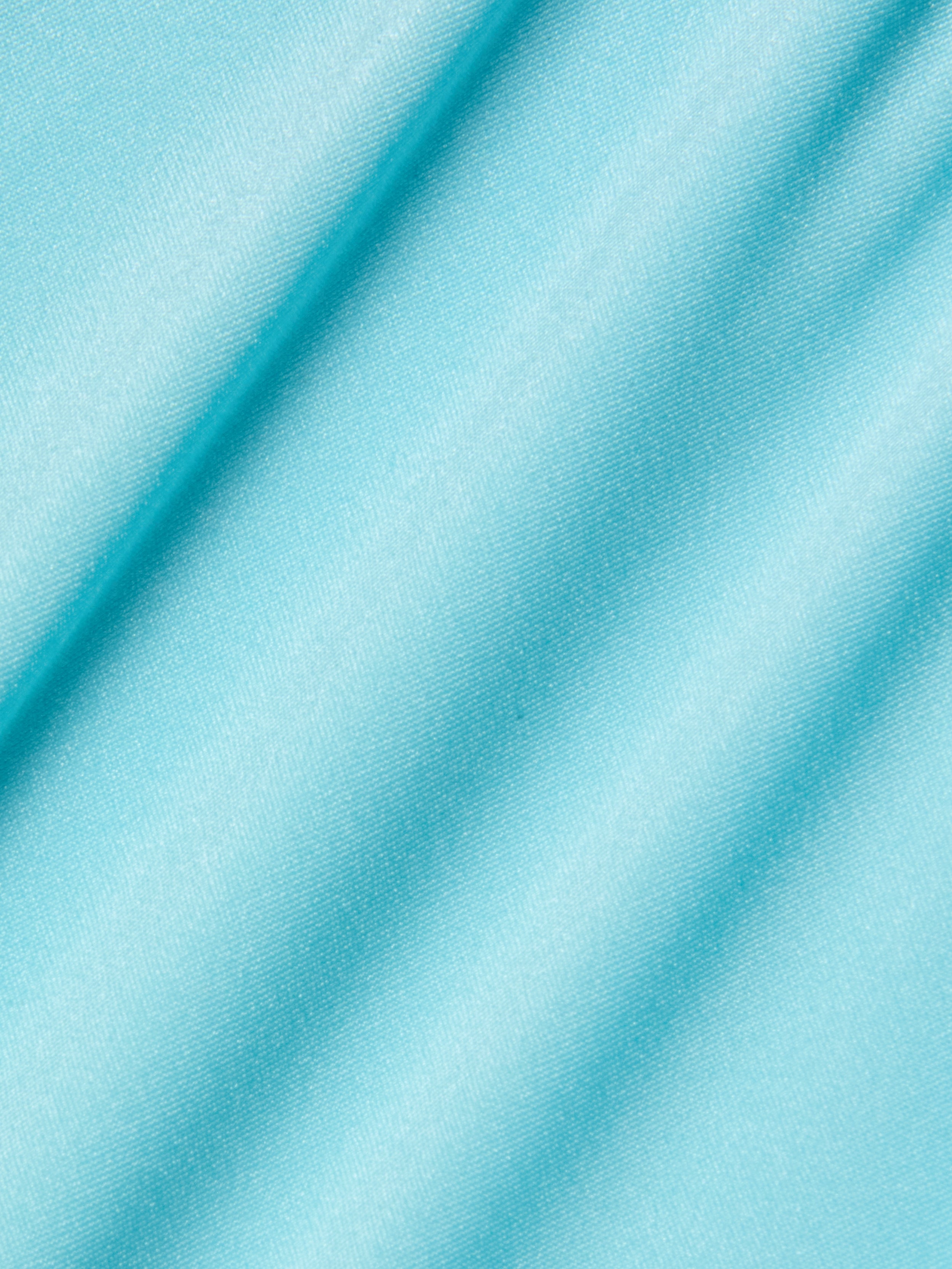 Close-up of the Violet String Bikini Bottom in an ice blue shade, featuring smooth fabric with a soft sheen and diagonal folds that create gentle shadows across the material.