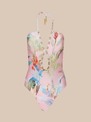 The Opus Halter One-Piece Swimsuit features a pink tropical floral print, deep V-neck with shell accents, and a tassel-tied halter neck, shown on a beige background.