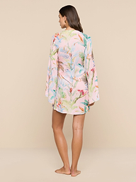 A woman stands barefoot facing away, wearing the Kohima Cover-Up Dress—a light, floral-patterned long-sleeve dress with subtle bell sleeves—set against a plain white background.