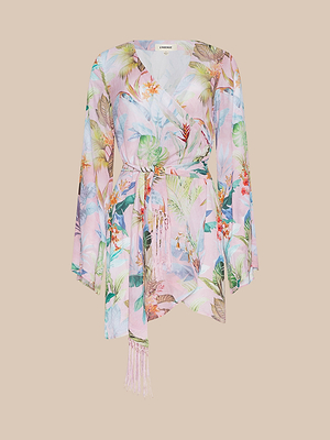 The Kohima Cover-Up Dress is a long-sleeved, pastel pink wrap dress with a tropical floral print, belted waist, tassel-trimmed tie ends, shown on a plain beige background.