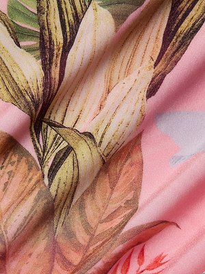 Close-up of the Violet String Bikini Bottom’s fabric, showcasing a floral and palm leaf print with large pale yellow and orange motifs on a pink background, detailed by soft folds and shadows for added texture.