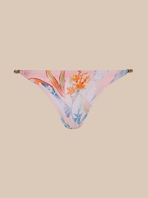 Violet String Bikini Bottom with UPF 50 protection, featuring a palm leaf and tropical floral print in orange, yellow, and blue. Designed with thin side straps and gold ring accents, shown on a solid beige background.