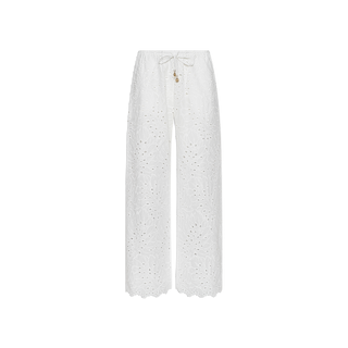 The Geraldine Eyelet Cover-Up Pant in white cotton features wide legs, eyelet lace, a scalloped hem, a drawstring tie waist with decorative charm detail at the front, and is displayed on a plain white background—perfect resort wear for effortless elegance.
