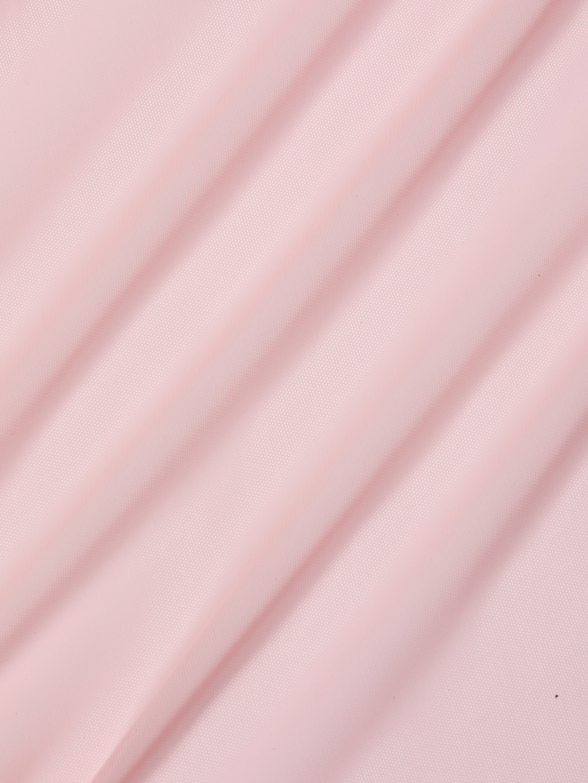 The Ambala Cover-Up Top features light pink sheer mesh fabric with soft diagonal folds, creating gentle shadows and a smooth, textured surface.