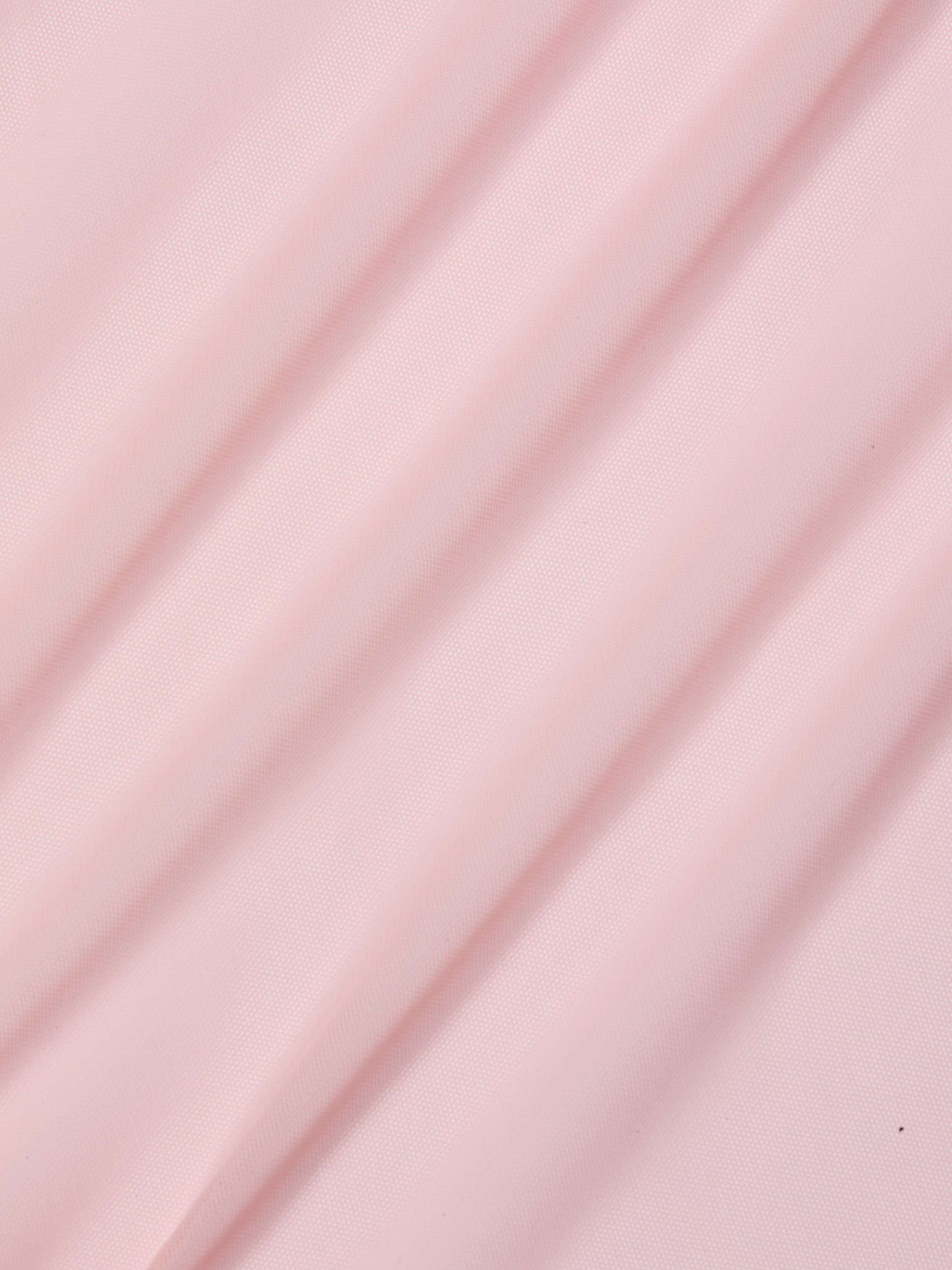 The Ambala Cover-Up Top features light pink sheer mesh fabric with soft diagonal folds, creating gentle shadows and a smooth, textured surface.