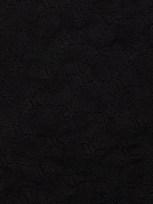 Close-up of the black, textured fabric of the Annabelle Bikini Top, featuring a subtle geometric pattern and highlighted surface that recalls high-quality UPF 50 swimwear.
