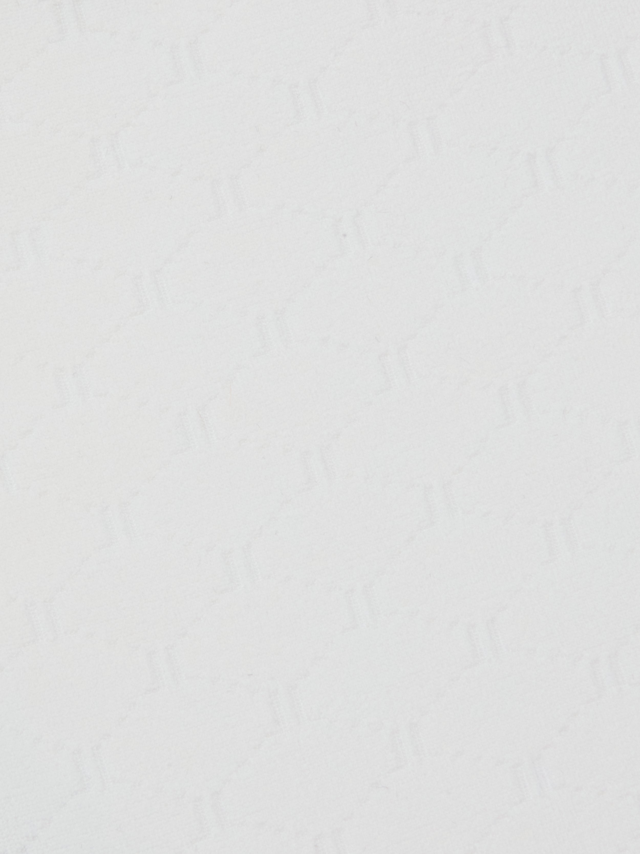 Close-up of the Annabelle Bikini Top’s white textured surface, featuring a subtle geometric pattern of repeating zigzag, triangle, and diamond shapes. The faint, monochromatic design adds gentle depth and visual interest to the otherwise simple background.
