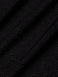 Close-up of the Violet String Bikini Bottom’s black fabric, featuring a subtle textured pattern and diagonal folds that create shadows and highlights across the material.