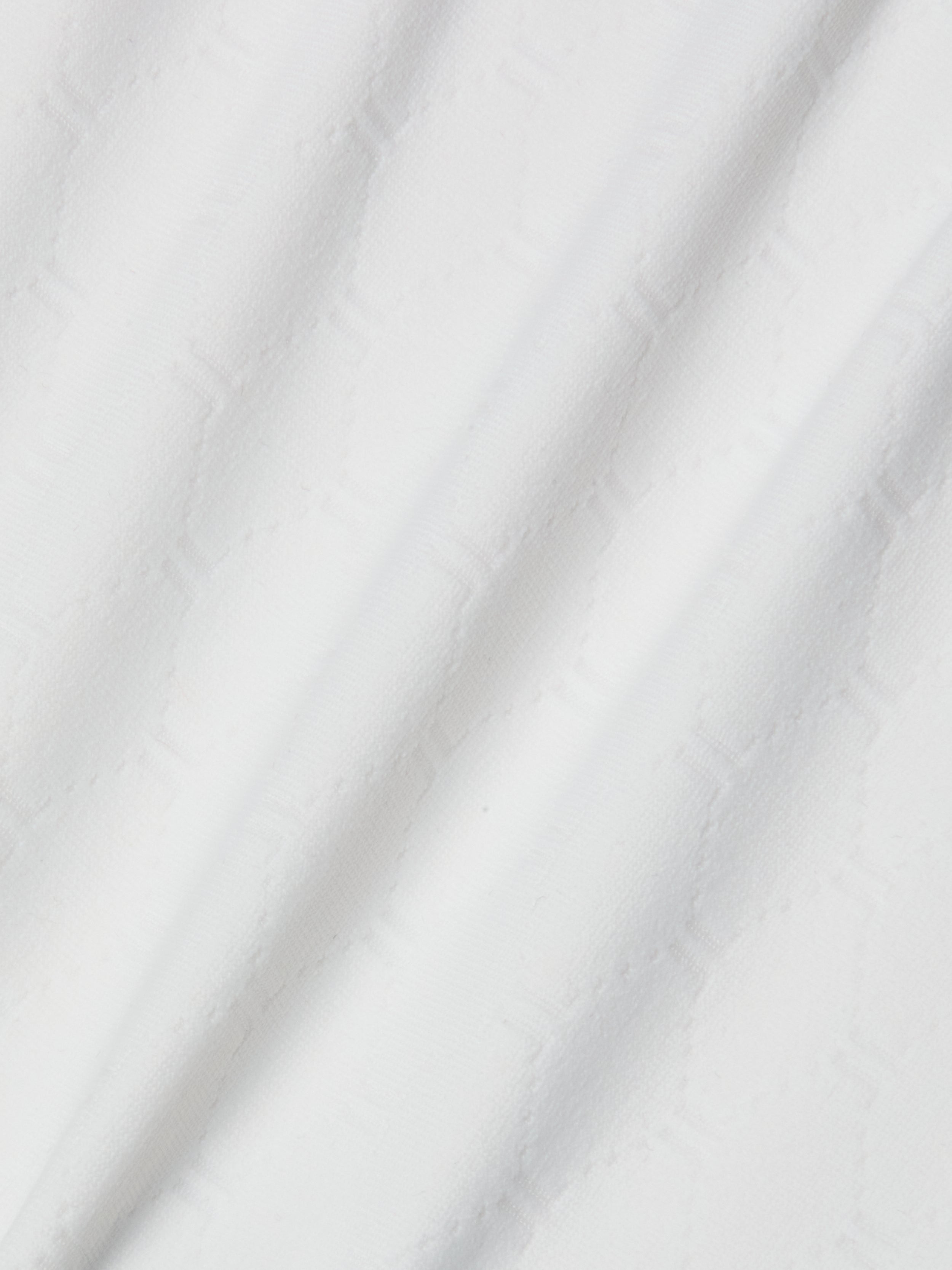 A close-up of white textured fabric with a subtle geometric hexagon pattern and soft diagonal folds, similar to the material used in the Violet String Bikini Bottom, which offers moderate coverage and UPF 50 protection.