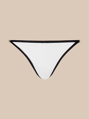 The Violet String Bikini Bottom features a white design with black trim and small gold accents, offers moderate coverage and UPF 50 protection, and is shown against a plain beige background.
