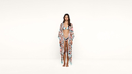 A woman stands barefoot against a plain white background, wearing a pastel-colored bikini with a matching long, sheer cover-up.