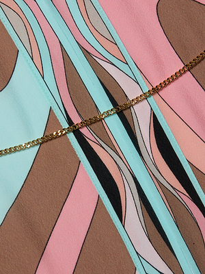 The Kara Kimono Cover-Up showcases abstract swirls in pastel blue, pink, and brown, accented by a diagonal gold chain. Its retro geometric design makes it an ideal modern beachwear piece or a stylish cover-up.