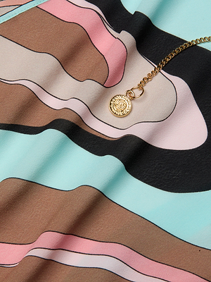 The Elise Cover-Up Dress, crafted from water-safe crepe with a pastel blue, pink, brown, and black abstract swirl print, features a smooth texture and diagonal design for a modern appeal.