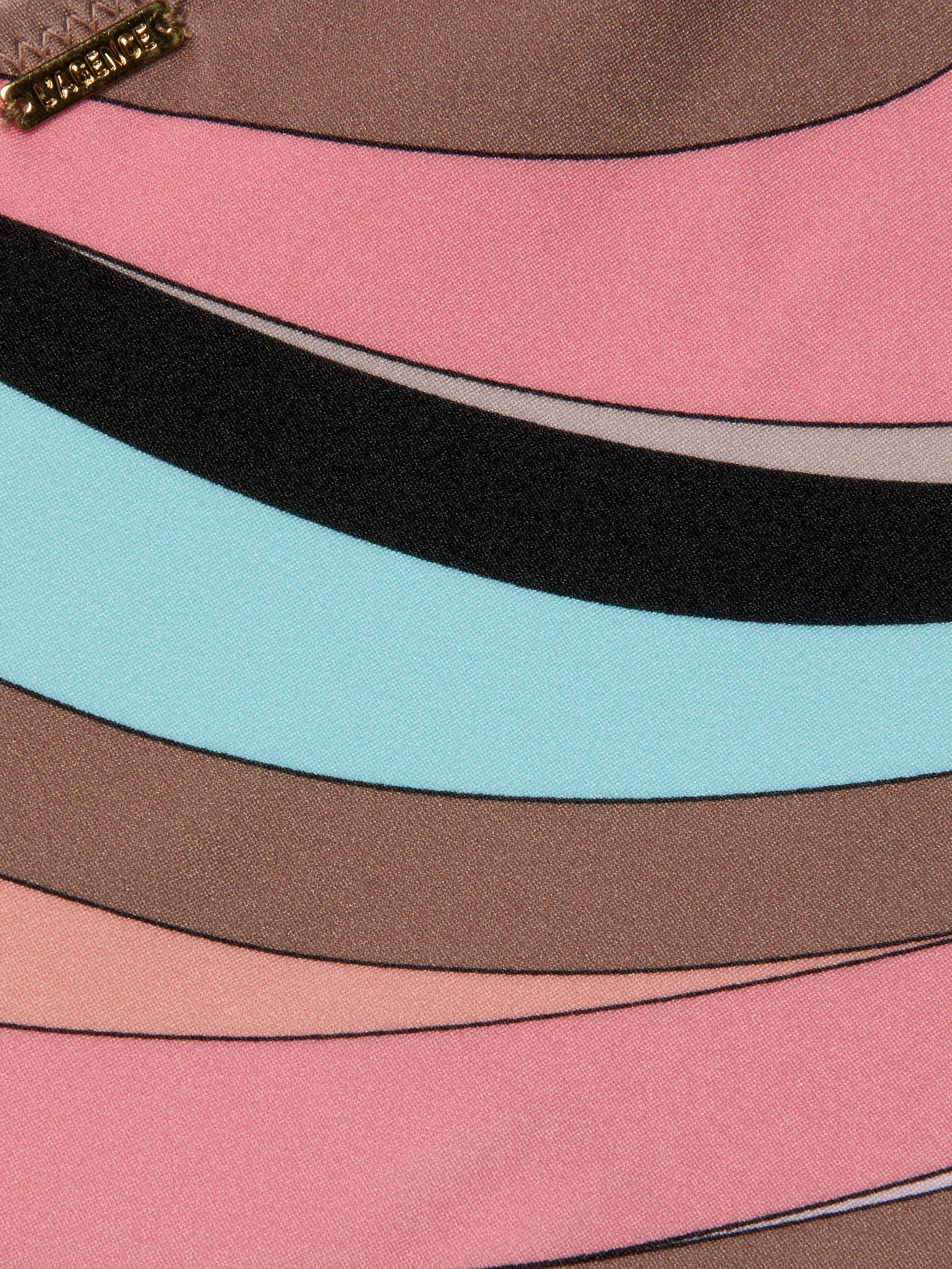 Le bas de bikini Nicole présente un imprimé abstrait en forme de tourbillon avec des rayures incurvées en rose, marron, bleu clair, noir et beige. Une petite étiquette métallique dorée avec texte en relief orne la partie supérieure gauche. Le tissu a une texture lisse et brillante.