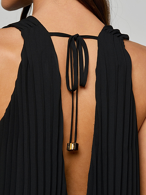 Close-up of a womans back in the Adalynn Cover-Up Dress—a black pleated chiffon style with an open back, tied at the top with black strings tipped in gold, ideal for chic getaways and effortless resort dressing.