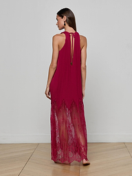 Barefoot and facing away, a woman models the Adalynn Cover-Up Dress—a sleeveless, floor-length red chiffon piece with delicate lace details—set against a plain white background; the perfect resort dress for your next getaway.