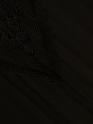 Close-up of the Sharon Cover-Up Pant in black, featuring a textured, triangular sheer lace overlay with intricate floral patterns on the left side, layered over smooth fabric.