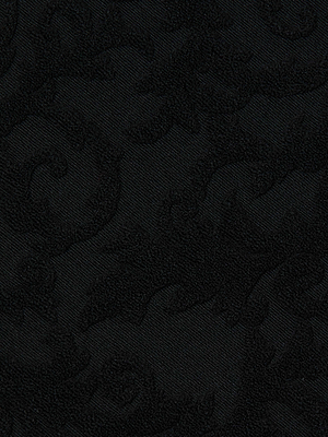 Close-up of the Amiya Cover-Up Short in black terrycloth, featuring a subtle raised floral or leaf pattern for an elegant, textured look. Its seamless monochrome design is perfect for a stylish resort-inspired outfit.